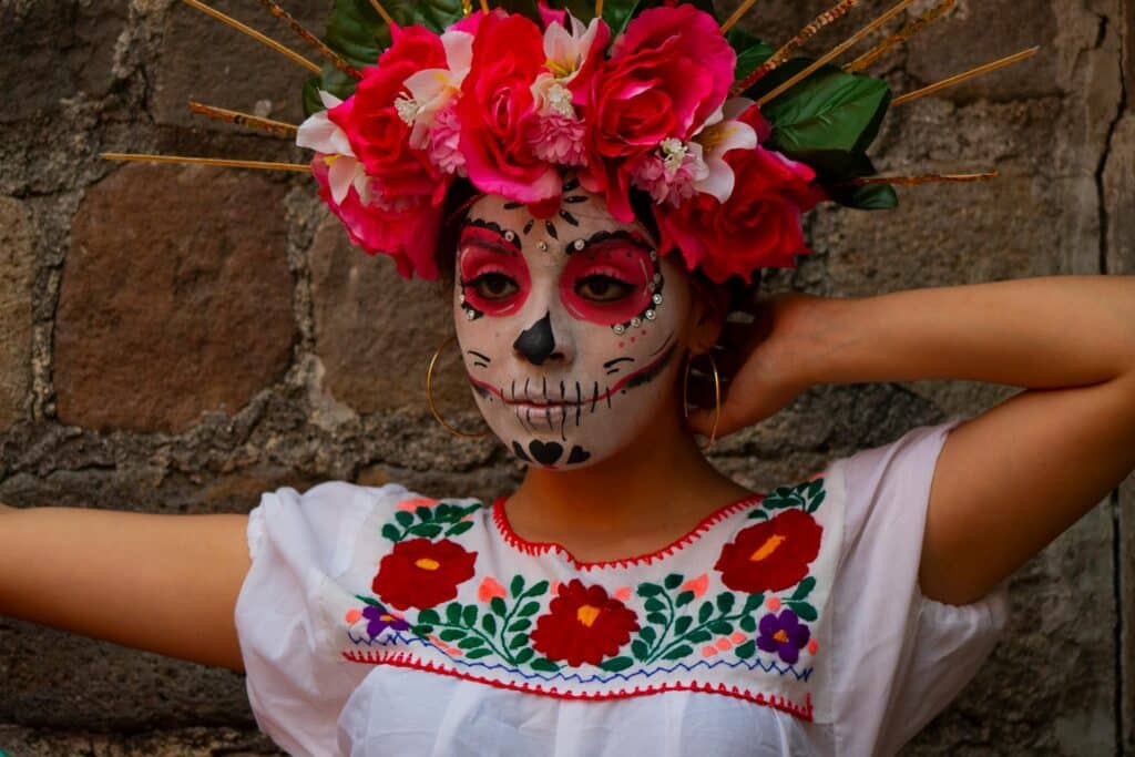 Dia De Los Muertos celebration - Mexican woman wearing traditional face painting and a crown of flowers.