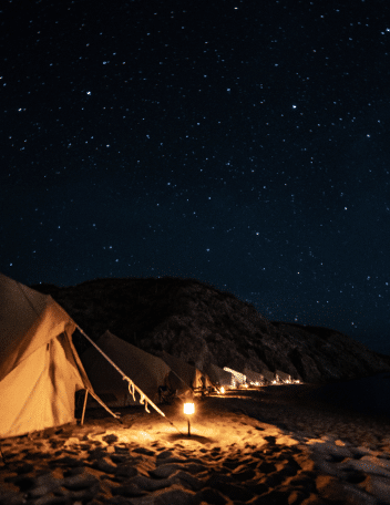 Beachfront safari glamping tents lit by lantern light under a star-filled night sky on Isla San José